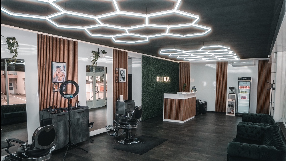 Stvarni interijer Barbershopa Blenda — drveni detalji, zelena sofa i geometrijska rasvjeta