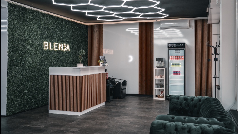 Recepcija Blende s drvenim letvicama, zelenim zidom i logotipom salona